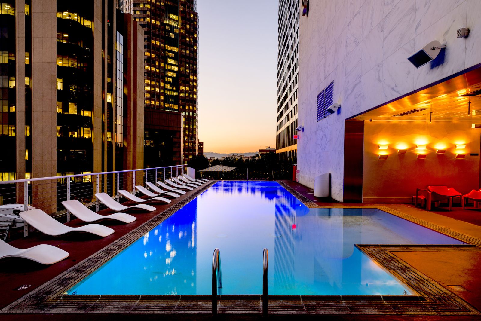 Swimming pool and outdoor deck beside buildings at dusk